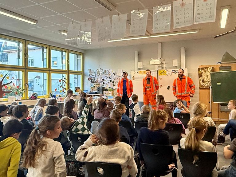 ZAKB beim Bundesweiten Vorlesetag Drei orange gekleidete Müllwerker vor Schulklasse