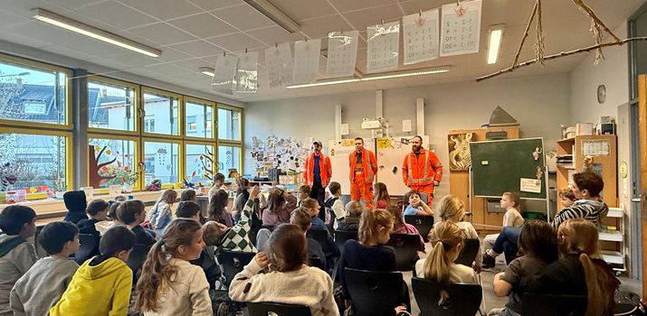 ZAKB beim Bundesweiten Vorlesetag Drei orange gekleidete Müllwerker vor Schulklasse