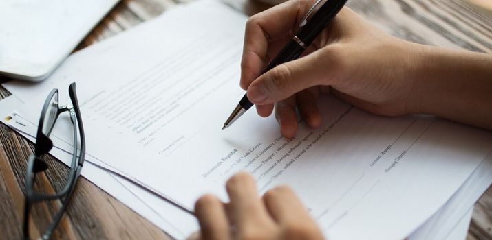 Symbolbild: Formular Hände mit Kugelschreiber über einem Formular-Papier