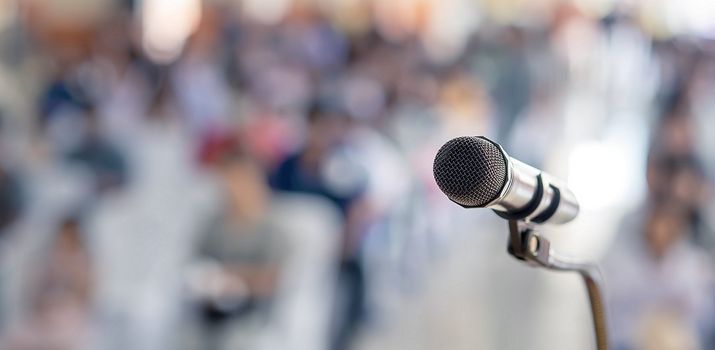 Symbolbild: Versammlung Redner-Mikrofon vor verschwommenem Auditorium